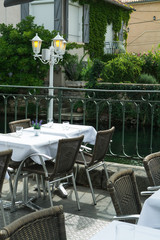 Empty cosy french street cafe or brasserie located on small river with served tables ready for visitors