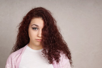 sad teenage girl looking depressed hiding half of her face behind long curly hair