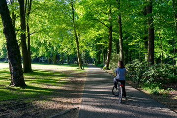 Jovem montada em bicicleta num passeio no meio de um parque