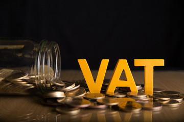 Vat Concept.Word vat put on coins and glass bottles with coins inside on black background.