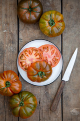 Reife farbige Tomaten zusammen mit einem Messer auf einem alten Holzuntergrund