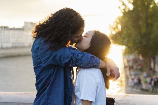 France, Paris, affectionate young couple kissing at river Seine at sunset