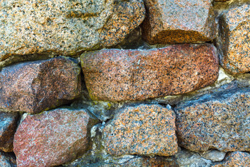 Ancient weathered wall constructed of natural cobblestone. Colorful horizontal image suitable for interior design, backdrop, wallpaper. Template background for advertising, products montage.