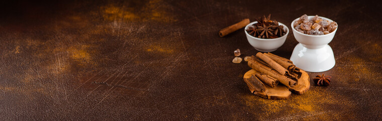 Cinnamon sticks, anise sprouts and caramelized sugar on a dark background. View from above. Close-up.