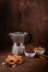 Cinnamon sticks, anise stars, caramelized sugar, coffee pot and milk jug on a dark background