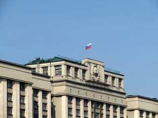 Fototapeta na wymiar Russian flag on the Parliament building in Moscow. State Duma of Russia against clear blue sky