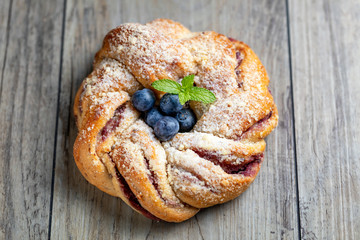 Blueberry pleated bun with powdered sugar and fresh berries o wooden background