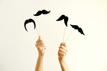 Movember concept. November is month of men health issues and prostate cancer awareness. Young woman holding paper moustache of different style on stick with two hands. Background, close up, copy space