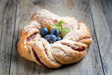 Blueberry pleated bun with powdered sugar and fresh berries.