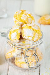 Cracked Lemon cookies in small glass jar, on white wooden background , vertical composition