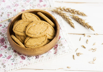 Cereal cookies in wooden plate with wheat ears
