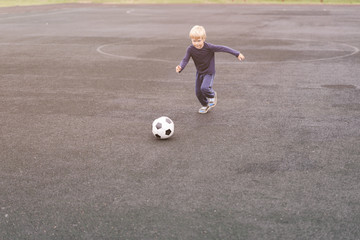 active lifestyle in a modern city - little boy playing with a soccer ball at the stadium