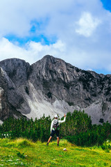 Beautiful alpine high mountains landscape, hiking young man. One male backpack tourist watching amazing green hills.