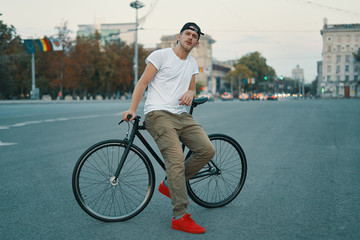 Portrait of young man walking with thoughtfully classic bicycle