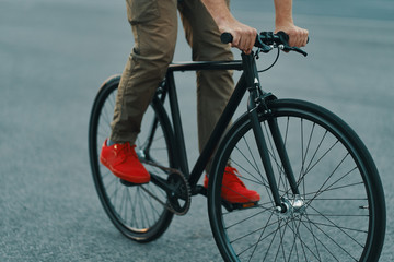 Fototapeta premium Closeup of casual man legs riding classic bike on city road