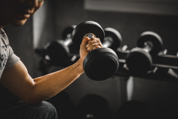 Close up of fit young hand caucasian big muscle in sportswear. Young man holding dumbbell during an exercise class in a gym. Healthy sports lifestyle, Fitness concept.