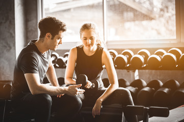 Fit beautiful young woman caucasian attractive fitness woman exercise with dumbbell by trainer in gym. Healthy, sport, lifestyle, Fitness concept.