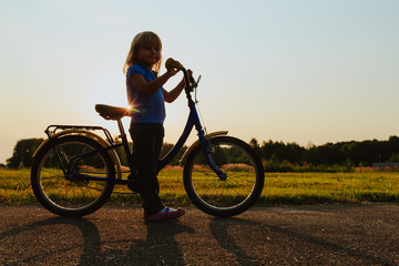 Fototapeta na wymiar little girl riding bike at sunset