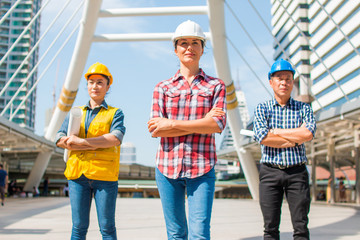 Three industrial engineer wear safety helmet standing on building outside. Engineering tools and...