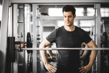 Fototapeta na wymiar Fit caucasian handsome young man and big muscle in sportswear. Young man standing and looking machine weight lifting in a gym. Healthy sports lifestyle, Fitness concept. with copy space