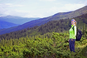 Smiling young woman with backpack standing   on mountin peak in Dragobrat , Carpathian mountains  ,Ukraine