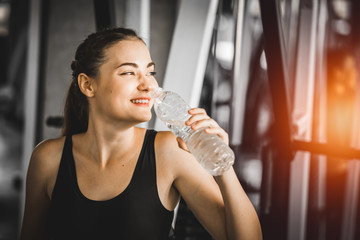 Fit young woman caucasian sitting and resting after workout or exercise in fitness gym. woman at gym taking a break and relax with water in sportswear. Fitness concept, Healthy, Sport, Lifestyle