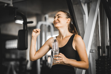 Fototapeta na wymiar Fit young woman caucasian sitting and resting after workout or exercise in fitness gym. woman at gym taking a break and relax with water in sportswear. Fitness concept, Healthy, Sport, Lifestyle