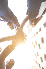 business, people and teamwork concept - smiling group of businesspeople standing in circle and putting hands on top of each other