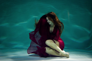 Woman under the water in a red dress.