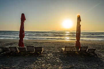 Sunbeds on the beach of Black Sea at sunrise, warm sunshine atmosphere