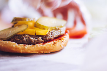 Have added slices of pickles, cheese and tomato in hamburger. Cooking burger concept