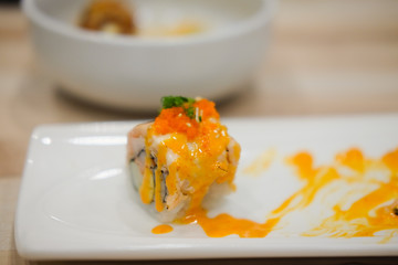 Sushi roll topped with spicy salmon slice