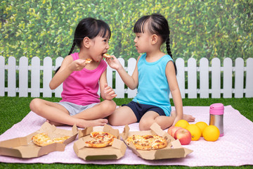 Asian Chinese little sisters eating pizza