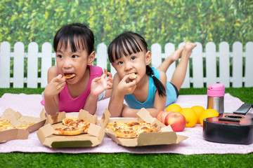 Asian Chinese little sisters eating pizza