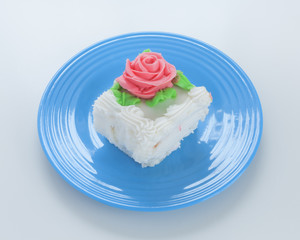 Obraz na płótnie Canvas Decorated cake square on blue plate.