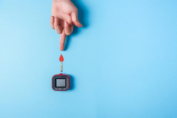 Blood test. Man's hand with red blood drop with Blood glucose test strip and Glucose meter