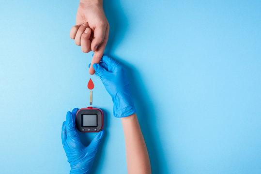 Nurse making a blood test. Man's hand with red blood drop with Blood glucose test strip and Glucose meter