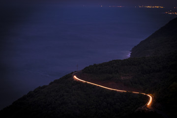 A brightly lit road twisting and curving up a mountain in Long Exposure.