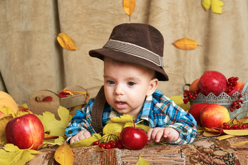 Fototapeta premium autumn concept - child boy lie on yellow leaves with fruits and vegatbles, red apples and pumpkins