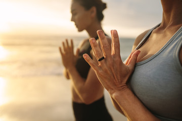 Women practicing yoga at the beach - obrazy, fototapety, plakaty