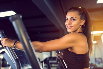 Fototapeta na wymiar Profile of young smiling woman exercising in health club