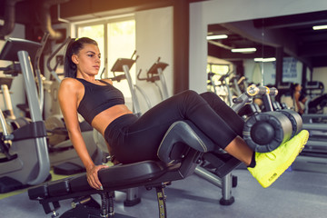 Fototapeta na wymiar Attractive Young woman doing sit up exercise with machine at the gym.