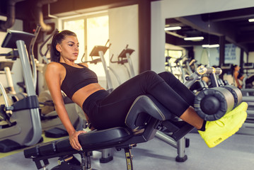 Naklejka na ściany i meble Attractive Young woman doing sit up exercise with machine at the gym.