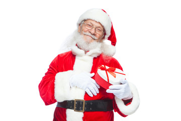 Christmas. Smiling Santa Claus in white gloves holds a red and white heart-shaped gift box with a red ribbon. Isolated on white background.