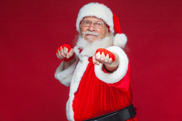 Fototapeta na wymiar Christmas. Santa Claus with red bandages wound on his hands for boxing imitates kicks. Kickboxing, karate, boxing. Isolated on red background.