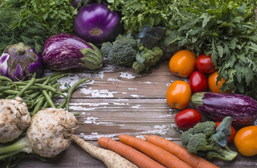 The set of natural organic vegetables for preparation vegetarian food - eggplant, tomatoes, carrots, green beans, celery on a wooden background.