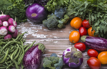Background with the set of natural organic vegetables for preparation vegetarian food - eggplant, tomatoes, green beans, radish on a wooden table.