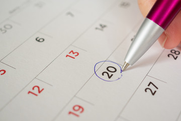 female hand holding pen circle mark on calendar page