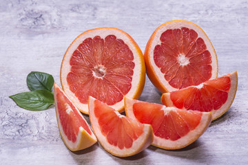 Fresh natural grapefruits with green leaf on a gray wooden table.