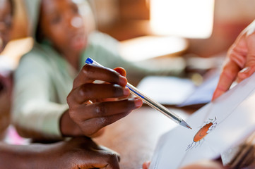 close up of hand of african boy in school with pen during lesson learning new figures